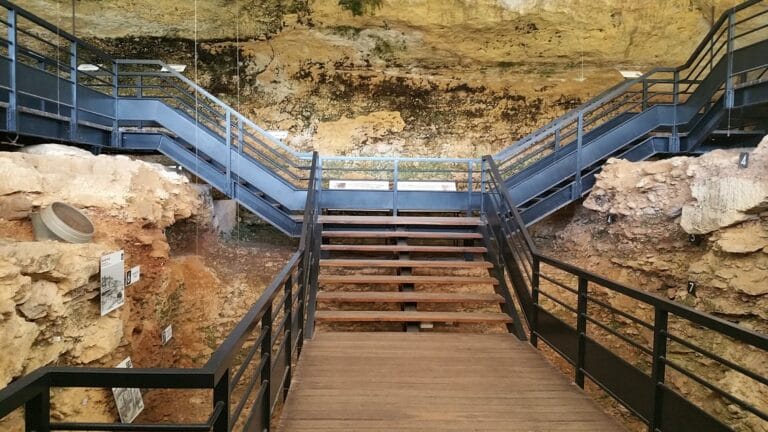 Stairs on a suspended walkway that allow visitors to walk over an archaeological excavation in the Pataud Rock Shelter, France.