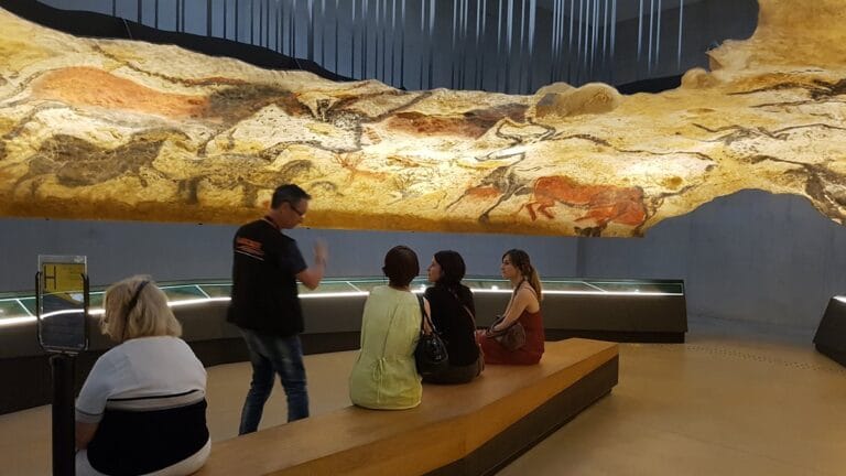 A guide talking to visitors in the replica of the Hall of the Bulls at the Lascaux IV replica.
