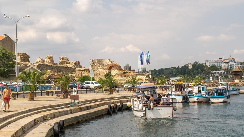 A boat comes into dock against the quay in Nessebar with ruins in the background.